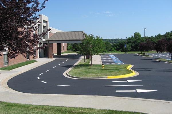 Freshly paved commercial parking lot with crisp white striping and directional arrows at office building in Woodbridge, NJ